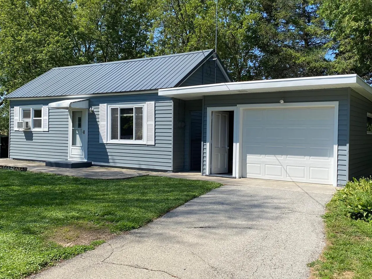 The ranch house after painting, siding in blue-gray with white trim and garage door.