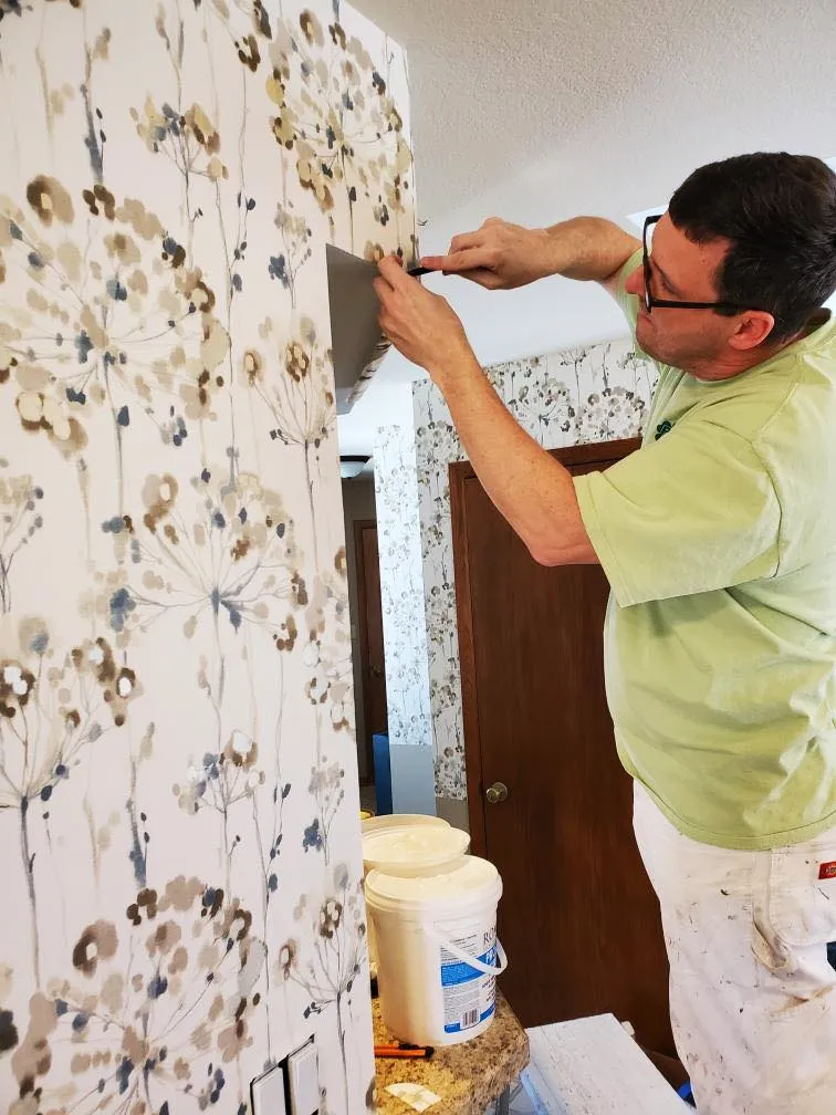 The professionals at RyanPatrick Painting & Decorating adding visual flair to an interior house room by skillfully applying wallpaper.